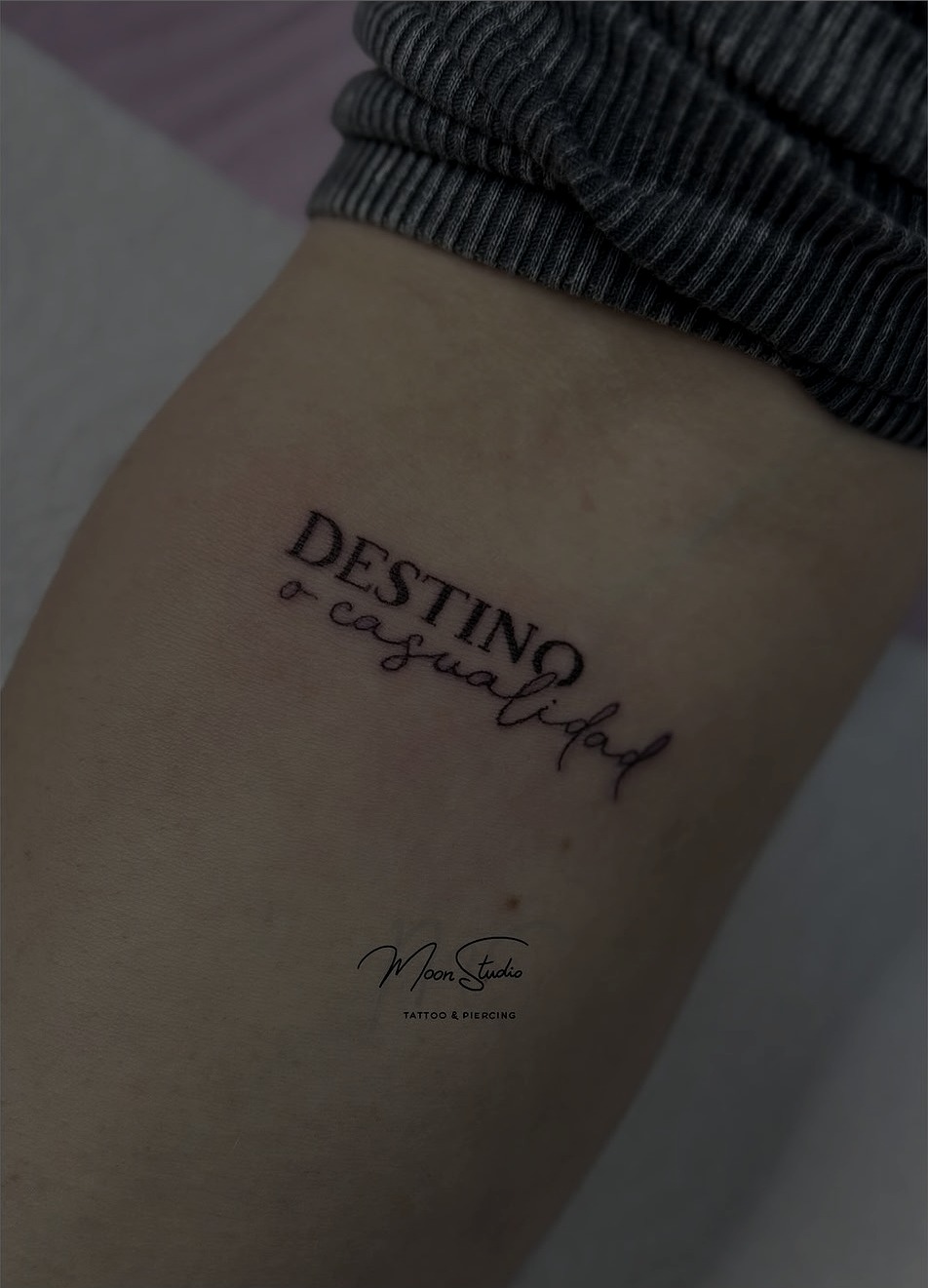 Tatuaje de lettering "Destino o casualidad" en el brazo, realizado en Moon Studio